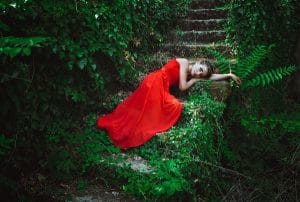 Beautiful Russian woman in a red dress lying on the steps alone